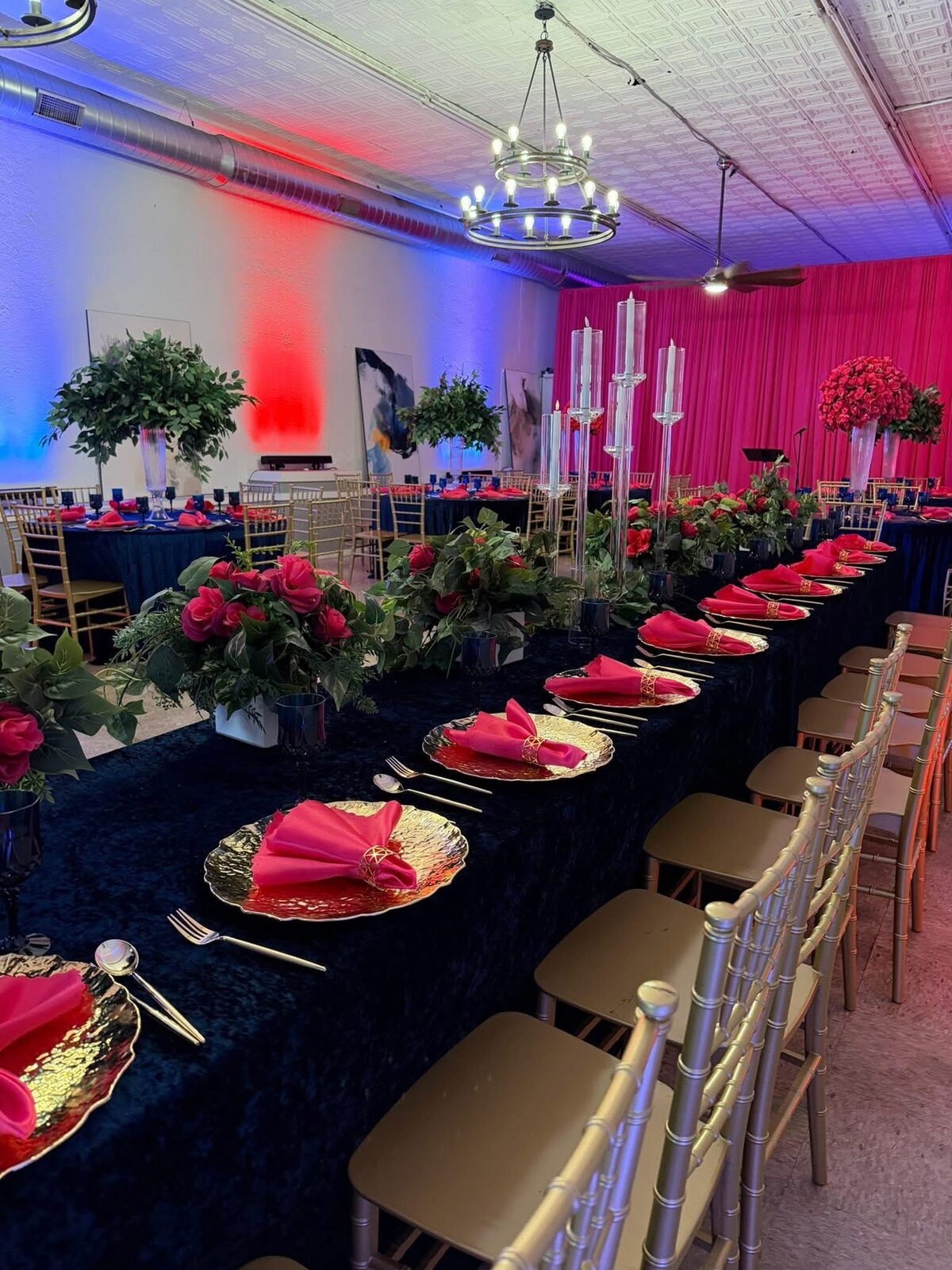 Banquet table with navy linens, gold chairs and red roses